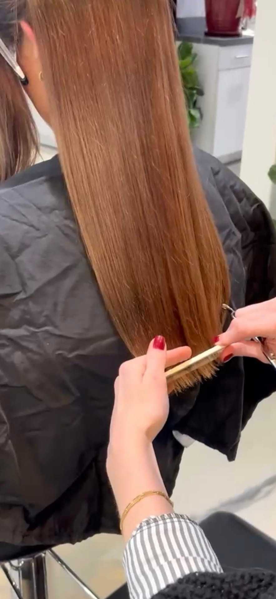 Hair being trimmed straight with scissors in a salon.